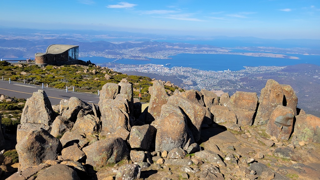 Wide panoramic view from the summit of Mount Wellington on a clear day, looking down over the city of Hobart, the Derwent River, and the Tasman Peninsula to the east.