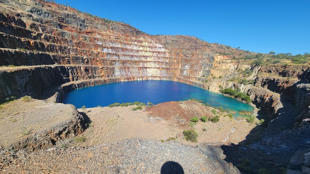 The vibrant blue radioactive lake in the abandoned Mary Kathleen Uranium Mine open cut pit, northwest Queensland, viewed from the tiered rock edge.