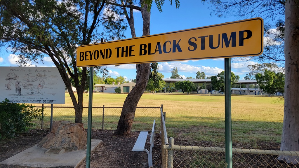 The iconic Beyond the Black Stump sign and petrified wood stump in Blackall Queensland on the Matilda Way road trip route.