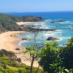 Elevated coastal view of a secluded sandy beach and ocean headland on a Brisbane to Sydney road trip