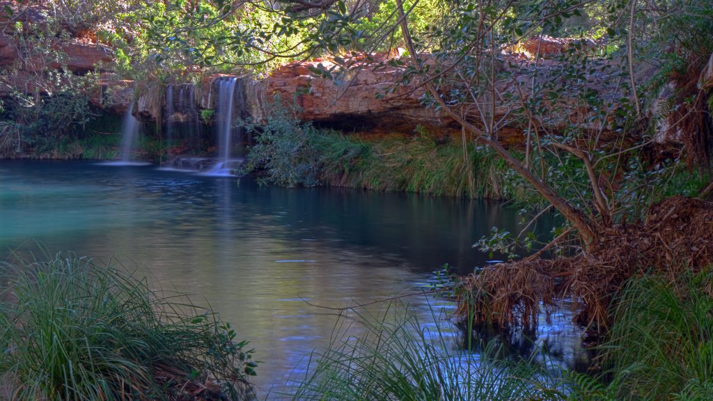 Tranquil waterfalls flowing into Fern Pool in Karijini National Park on the Pilbara and Coral Coast loop