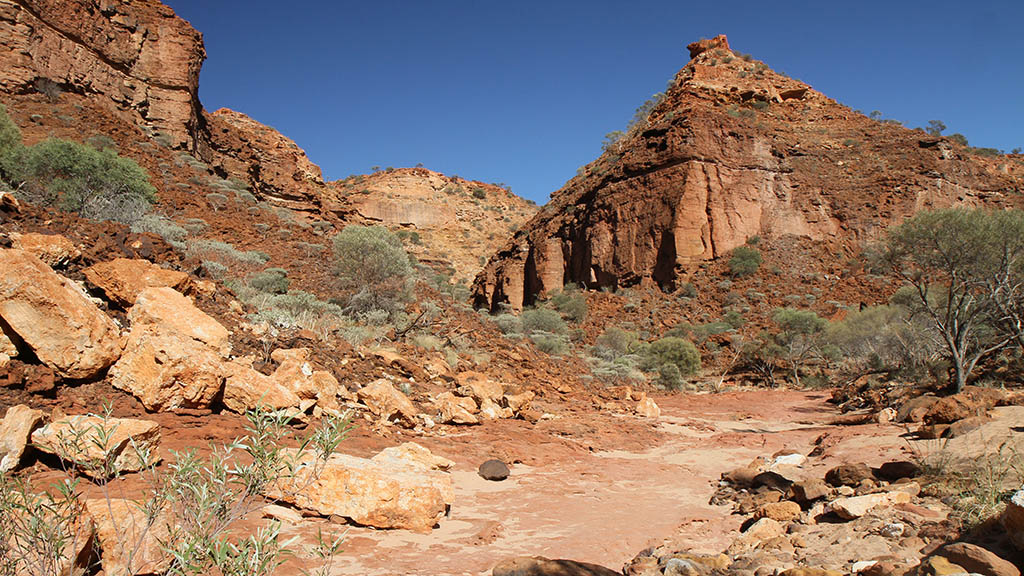 Rugged red sandstone escarpment and dry rocky creek bed near Temple Gorge Campground